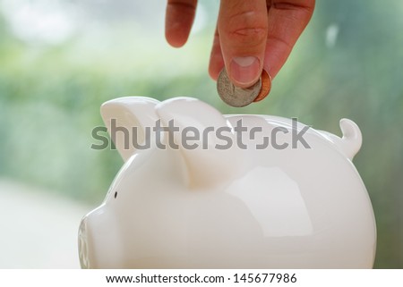 Piggy bank being loaded. Piggy Bank, Hand and Coin.