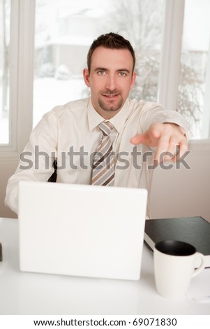 A business man at home office pointing at camera using laptop