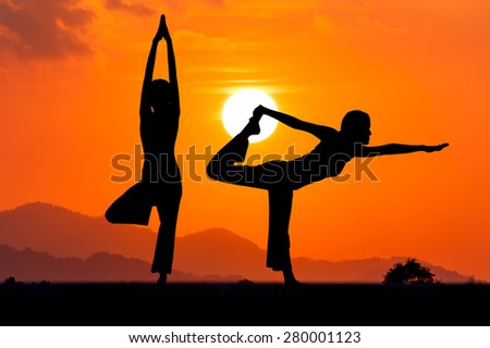 Silhouette young woman practicing yoga on the mountain at orange sunset