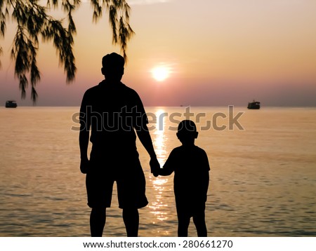 silhouette father hand hold his  son looking forward at the sea sunset background