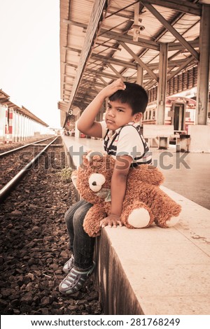 vintage Cute boy,sad sitting on a bench with teddy bear waiting someone