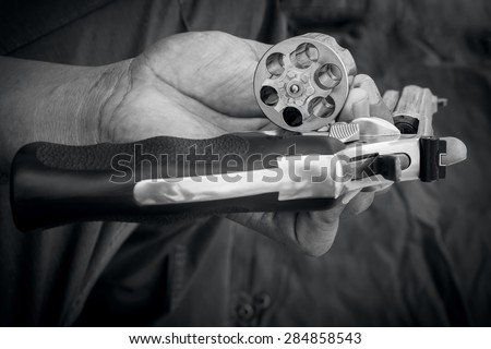 black and white of hand man holding show gun emptied storage cylinder of revolver handgun