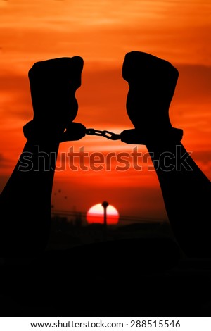 silhouette of hand men in shackle on sunset in city  background