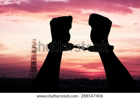 silhouette of hand man in shackle on big sunset background
