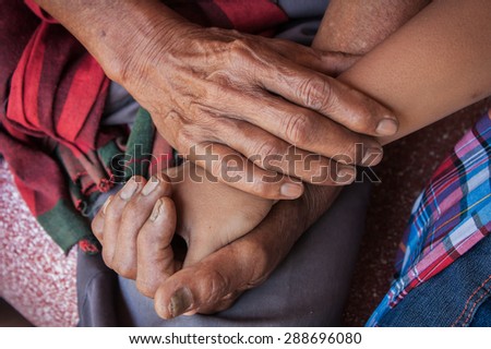 asian kids little boy hand touches and holds an old man wrinkled hands.
