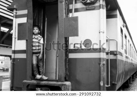 blurry abstract of the little boy standing alone and hand hold white bear at inner train ,black and white tone