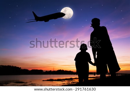 silhouette of father and son point look at to  full moon after sunset at  the river background