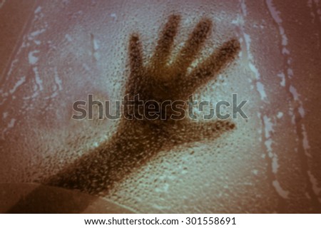 blurry abstract shadow of hand girl in water drop on glass,vintage tone