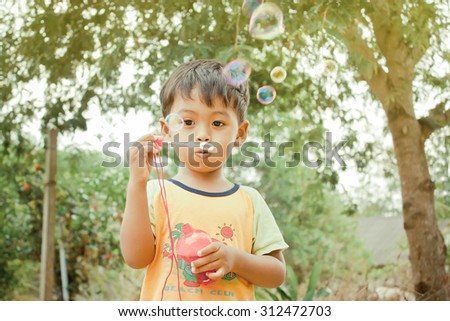 Little asian boy playing with bubble wand blowing soap bubbles,vintage tone