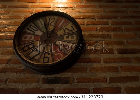 Clock on brick wall in dark room.