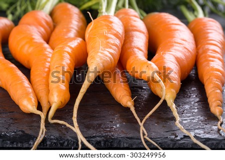 A bunch of fresh carrots on black slate background. Selective focus.