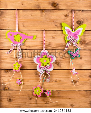 Spring decor -flower, bird and butterfly pendants on the wooden background.