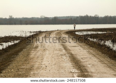 Man walking down the road in the winter in field