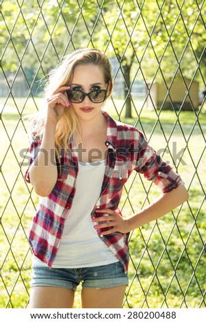 Beautiful trendy hipster girl looking over sun glasses