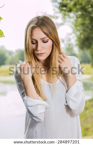 Girl in white dress outdoor, arms on shoulders, emotional