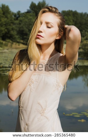 Beautiful blonde girl in white dress outdoor, emotive expression, eyes closed