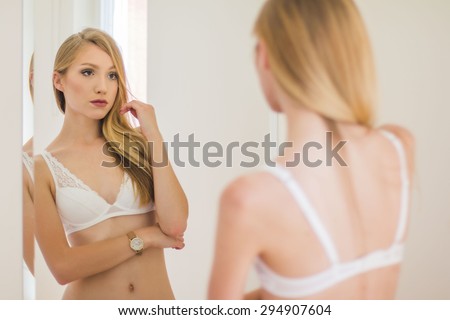 Sexy girl in white lace underwear looking in mirror