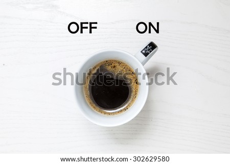 Cup of coffee on white desk, switched on, concept