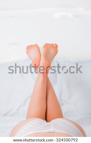 Sexy girl on the bed, legs raised up, part of the body