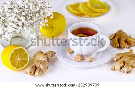 tea with a lemon and ginger in a white mug on a white background with small white flowers
