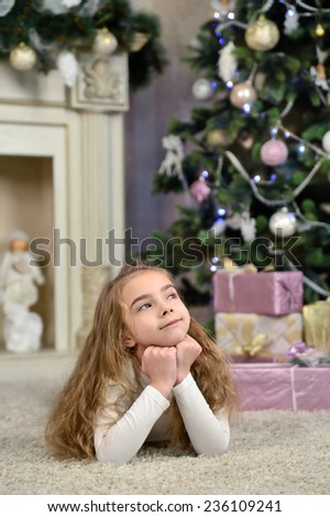 little girl dreaming near Christmas tree