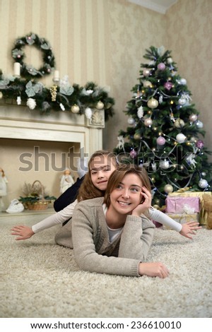 mother and daughter are dreaming near Christmas tree. Family holiday