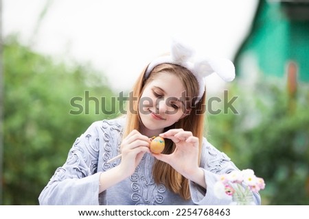 Smiling teen girl with rabbit bunny ears painting egg for Easter holiday. Happy child decorating eggs for Easter holiday. Selective focus.