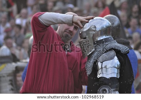 WARSAW, POLAND - MAY 01: Unidentified participant helps to remove the helmet during The International Festival of the Middle Ages \