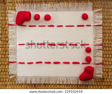 little red boots and beads on a linen napkin embroidered with red stitches with space for text on the wicker wooden background