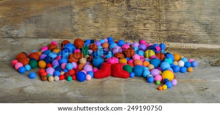 multicolored felted beads and red boots on the wooden background