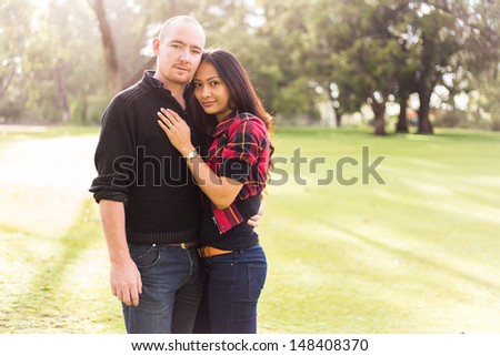 Happy young couple portrait, asian woman, caucasian man, hugging tenderly in a nice park