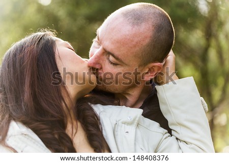 Romantic young couple, asian woman caucasian man, kissing tenderly in outdoor environment