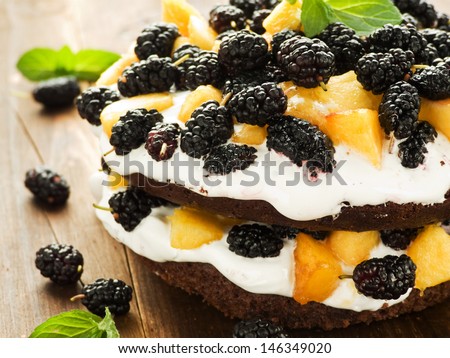 Chocolate cake with whipped cream, peach and mulberry . Shallow dof.