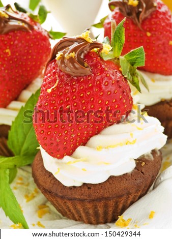 Chocolate cupcakes with strawberries, cocoa-nut paste and whipped cream. Shallow dof.