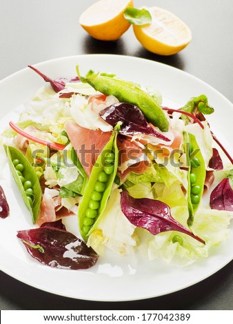 Salad with prosciutto, iceberg cabbage and green peas. Shallow dof.
