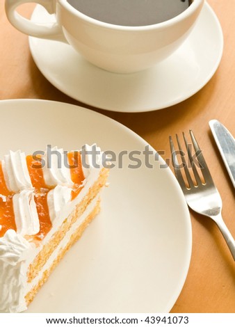 Cup of coffee and tasty cream cake with apricots. Viewed from above.