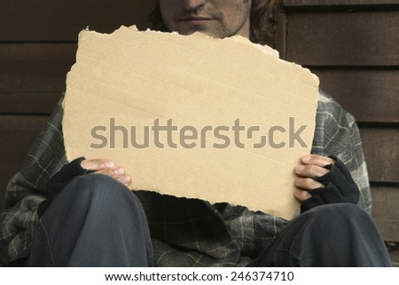 HOMELESS - A homeless beggar holding a blank cardboard sign