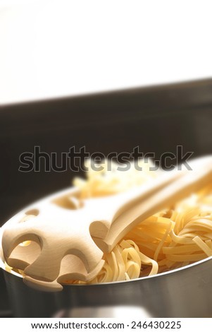 UNCOOKED PASTA AND TONGS - A close up shallow depth of field image of uncooked pasta and tongs
