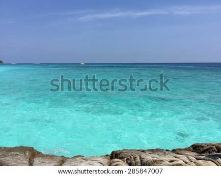Little boat in clear sea water with rock foreground
