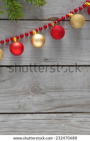 Red and gold christmas balls with red string of pearls on a wooden table