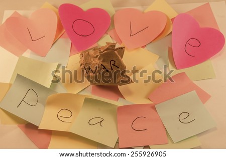 Love and peace written on post it notes with a screwed up peice of paper with war written on it, symbolising, peace and love conquering war, some images with colour removed to certain sections