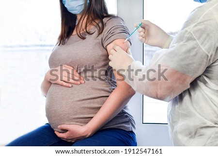 Pregnant Vaccination. Pregnant Woman In Face Mask Getting Vaccinated in Clinic. Doctor Giving Corona Virus Vaccine Injection Patient. Covid-19 Flu Protection.