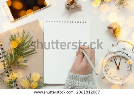 Back to life, goal list concept. Woman's hand writing in empty notebook. Resolutions, plan, goals, checklist, idea concept. Top view, flat lay, copy space. 2022. Christmas, New Year.