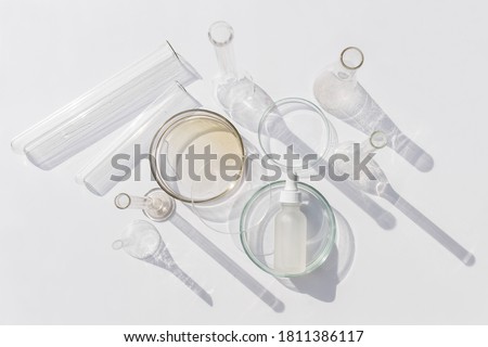Top view of laboratory glassware and cosmetic glass bottle on grey background. Natural medicine, cosmetic research, bio science, organic skin care products.