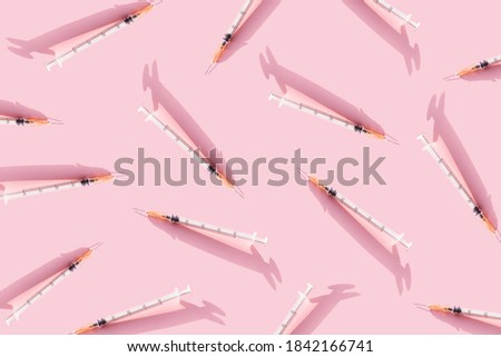 Creative medicinal pattern from syringes of pink background. Colorful concept of New Corona virus 2019-nCoV or COVID-19 vaccine. Flat lay, top view, copy space.