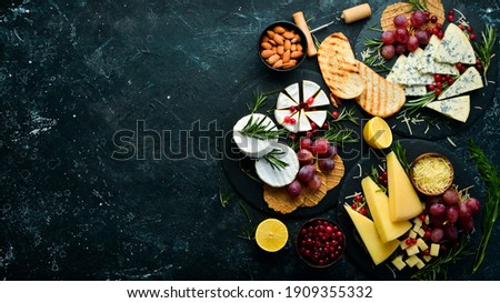 Cheese. Slices of cheese on plates: brie, blue, gorgonzola, parmesan and maasdam on a black stone background. Free copy space. Top view. Сток-фото © 