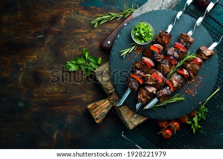 Traditional Kebab. Juicy pork skewers with vegetables on a black stone plate. Barbecue. Top view. Free space for text.