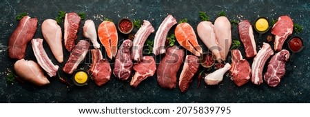Set of various classic, alternative raw meat, veal beef steaks, pork, chicken fillet, fish, salmon steak. Top view. On a black stone background.