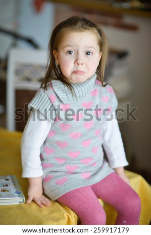 little girl with positive emotions sitting at the table upset