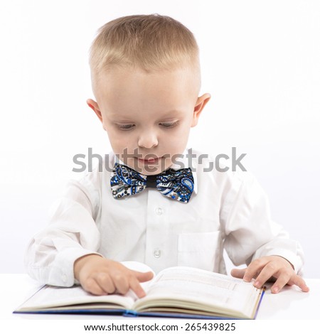 funny little boy sitting at the table and a book review. portrait on white background.
